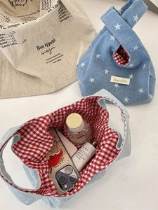 Denim knot bag with star print and red checkered lining, showing storage capacity