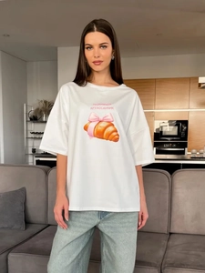 Λεπτομέρεια λευκού βαμβακερού t-shirt με στάμπα κρουασάν και ροζ φιόγκο σε στυλ chic