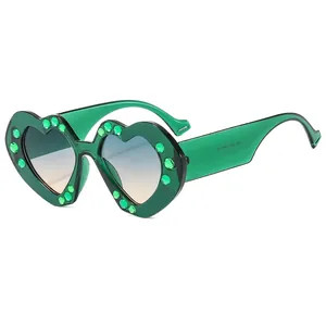 Modern heart-shaped sunglasses with green rhinestones and blue-orange gradient lenses