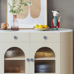 Close-up of ceramic drawer knobs with blue floral patterns on a stylish cabinet