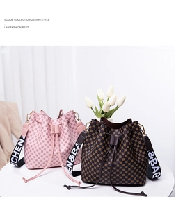 Close-up of pink and brown drawstring bucket bags with printed straps on a white table