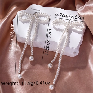 Detail view of pearl bow earrings with long tassels on silk showing 15.5cm length