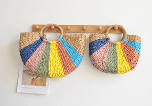 Detail of colorful woven straw handbags with semi-circle design and round handles
