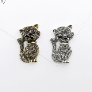 Golden and silver metal cat shaped pendants with textured surface on white background