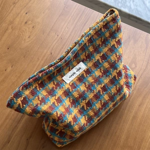 Detail of the woven plaid makeup bag with yellow and blue houndstooth pattern