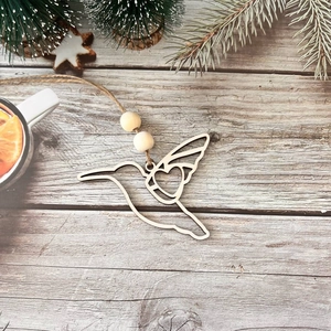 Detail of laser-cut wooden hummingbird ornament with heart design on vintage wood background