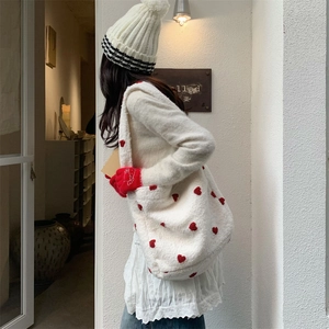 Outdoor shot of a white plush heart tote bag with lamb-like fur and red embroidery