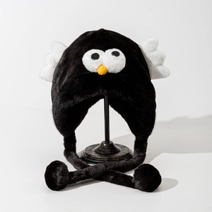 Close-up of black plush bird-themed earflap hat with white wings and pom-pom ties