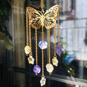 Close-up of golden butterfly suncatcher with colorful crystal prisms and metal chains