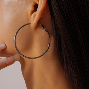 Macro side view of a large gunmetal geometric hoop earring worn by a female model