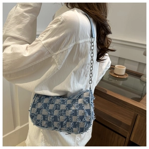 Detail of denim crossbody bag with checkerboard pattern and silver chain on model