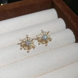 Detail of gold snowflake stud earring with pearls and sparkling zircon on velvet