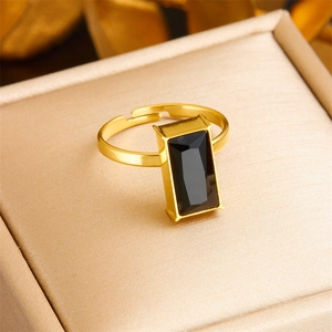 Macro view of gold adjustable ring with black rectangular gem in a beige gift box