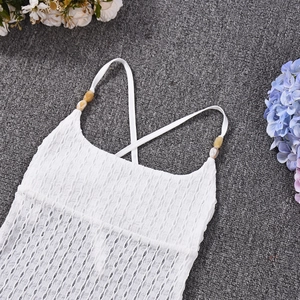 Detailed view of white pleated fabric with thin straps and decorative bead accents