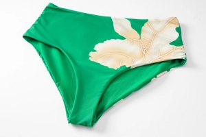 Detail view of high-waisted green bikini bottom featuring white floral print and ruching