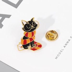 Close-up of creative black cat enamel pin with striped scarf and letter envelope
