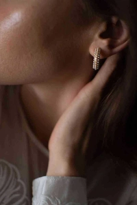 Détail de créoles à trois rangs de perles plaquées or 18 carats sur le mannequin