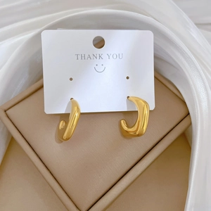 Polished titanium steel golden C-shaped hoop earrings on white jewelry display card