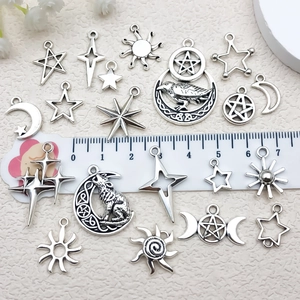 Antique silver celestial alloy charms with sun, moon and stars next to a white ruler