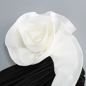 Detail of the oversized white fabric rose and black pleated satin on the evening gown