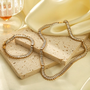 Close-up of gold-plated tennis necklace and bracelet set with clear rectangular zircon