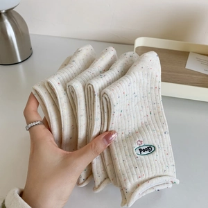 Vue détaillée de chaussettes en maille crème avec broderie de lettres 'Good' vertes