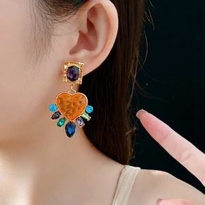 Détail de boucles d'oreilles vintage dorées avec gemme violette et breloques coeur
