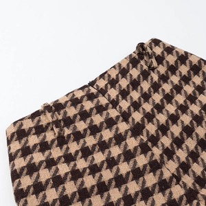 Detailed macro view of the brown houndstooth wool fabric texture and waistband loop detail