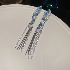 Detailed shot of long butterfly tassel earrings with blue accents and white faux pearls