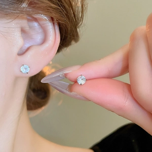 Close-up of minimalist four-prong silver stud earrings with sparkling clear cubic zirconia