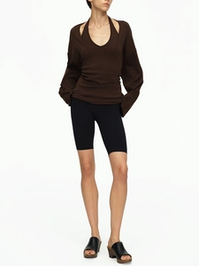 Detail of off-shoulder dark brown long sleeve top with black biker shorts on model
