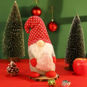 Christmas gnome plush with red knit hat and pink heart on a rustic wooden base