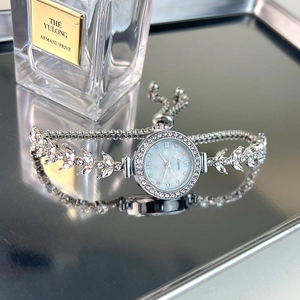 Detail of luxury silver rhinestone quartz watch with leaf bracelet on reflective tray