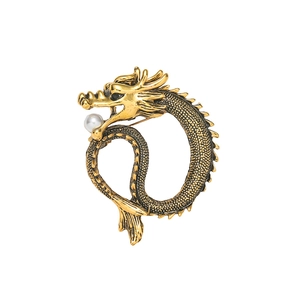Vintage golden dragon totem brooch with pearl accent on a minimalist white background