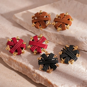 Vintage woven faux leather compass earrings in brown, red, and black on stone background