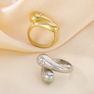 Close-up of gold and silver snake head rings with pavé diamonds on silk background