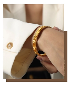 Detail of 18k gold plated clover flower bangle with embossed texture on female wrist
