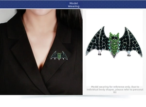 Detailed view of a Gothic bat brooch with green rhinestones on a black suit lapel