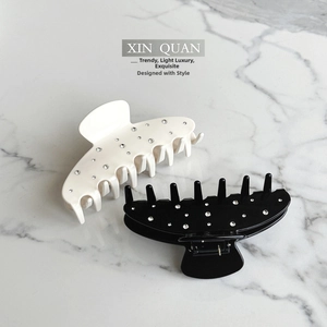 Detail view of glossy black and white hair claws with sparkling inlaid rhinestones