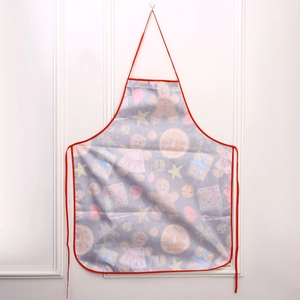 Detail of Christmas apron featuring gingerbread and gift patterns with red neck strap