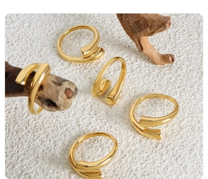 Detail of minimalist gold open rings arranged on white stone with natural wood branch