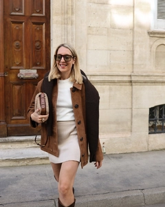 Détail d'une veste vintage en daim marron associée à une robe en maille dans une rue chic