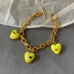 Detail of gold chain necklace with three translucent yellow heart glass pendants