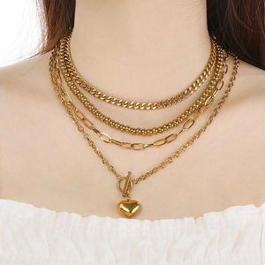 Gros plan d'un collier multicouche en acier doré avec pendentif cœur et fermoir OT chic
