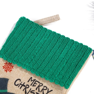 Close-up of green knit cuff and burlap Christmas stocking with red snowflake embroidery