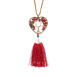 Detail of handmade heart tree of life pendant with red stones and long silk fringe