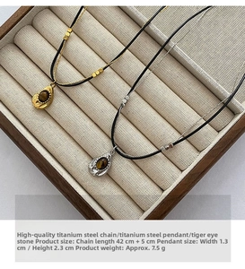 Detail of water-drop tiger eye pendants in gold and silver finish on display