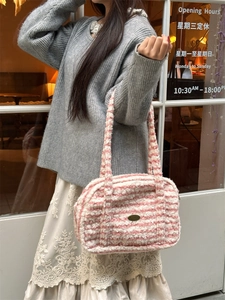 Gros plan du sac bandoulière en peluche à rayures rose et blanc avec emblème en métal
