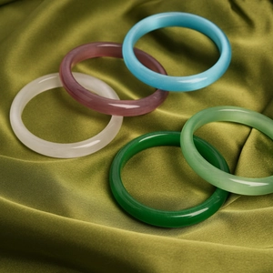 Detail view of multi-colored cat-eye stone bracelets on pleated green silk fabric