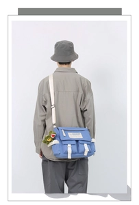 Sky blue messenger bag on model featuring a cute dinosaur plush charm and canvas texture